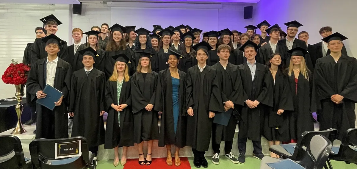 Schülerinnen und Schüler posieren in Robe für ein Foto.